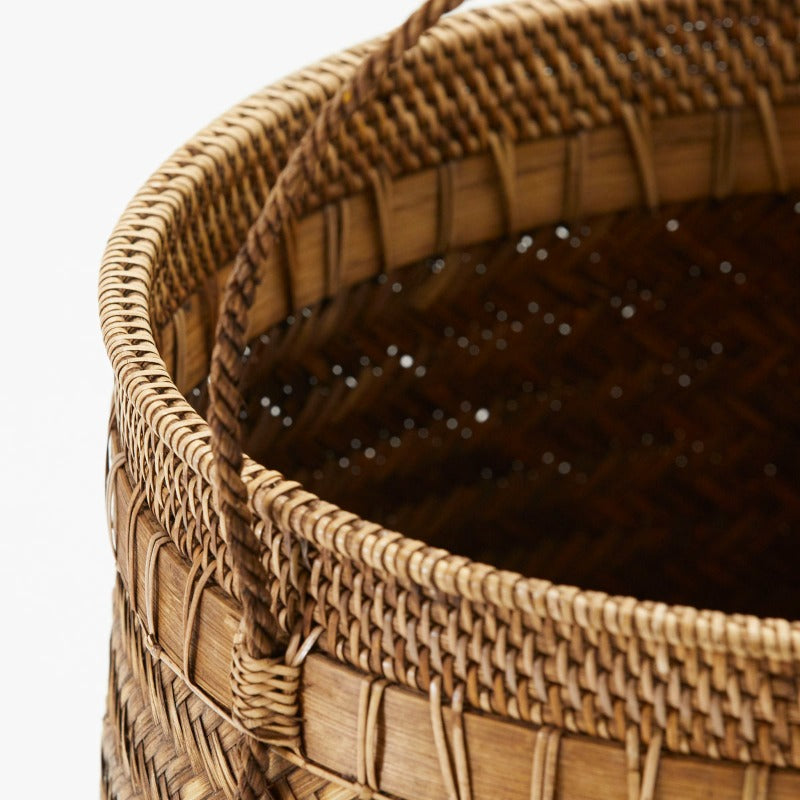 Hand-woven stylish basket with handles. The beautiful mixture of bamboo and rattan patterns is a testament to good craftsmanship. The golden brown color adds warmth to the home. Put blankets, magazines or a green plant in it. There is also a slightly smaller brother in the same basket. 